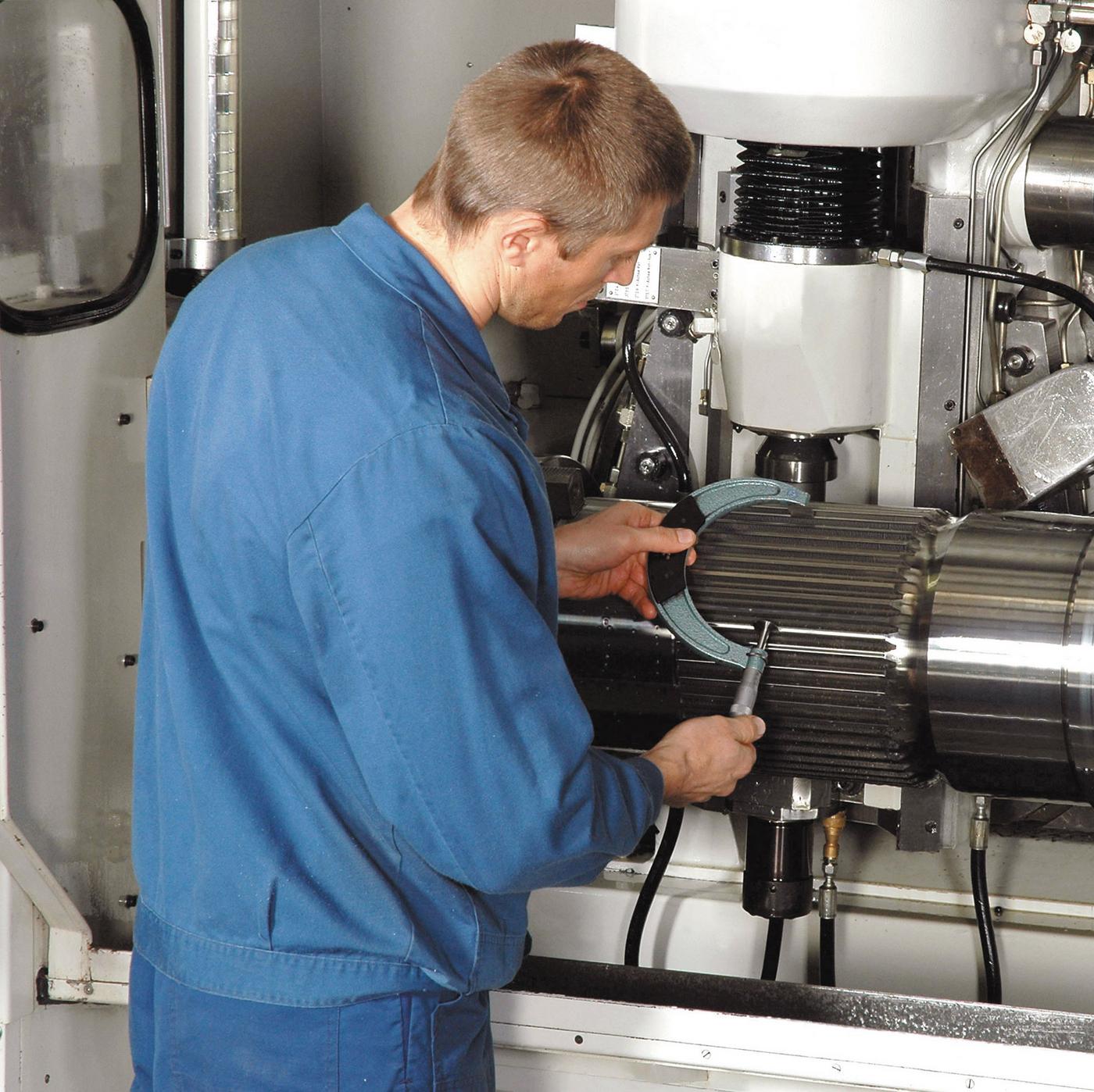 Mitarbeiter überprüft das Fräsergebnis in der Fräsmaschine